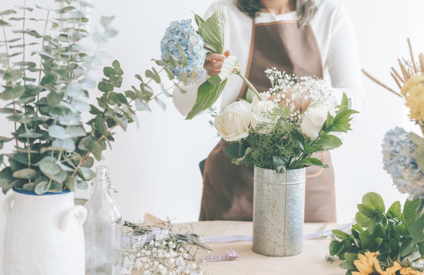 Professional flower designer arranging seasonal blooms in a bright commercial space